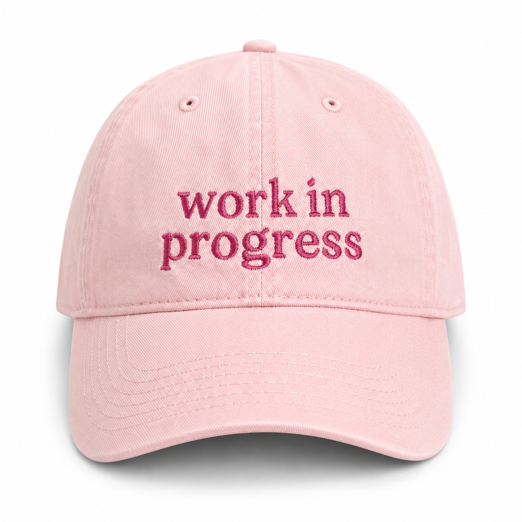 Pink cap with 'work in progress' text on a white background