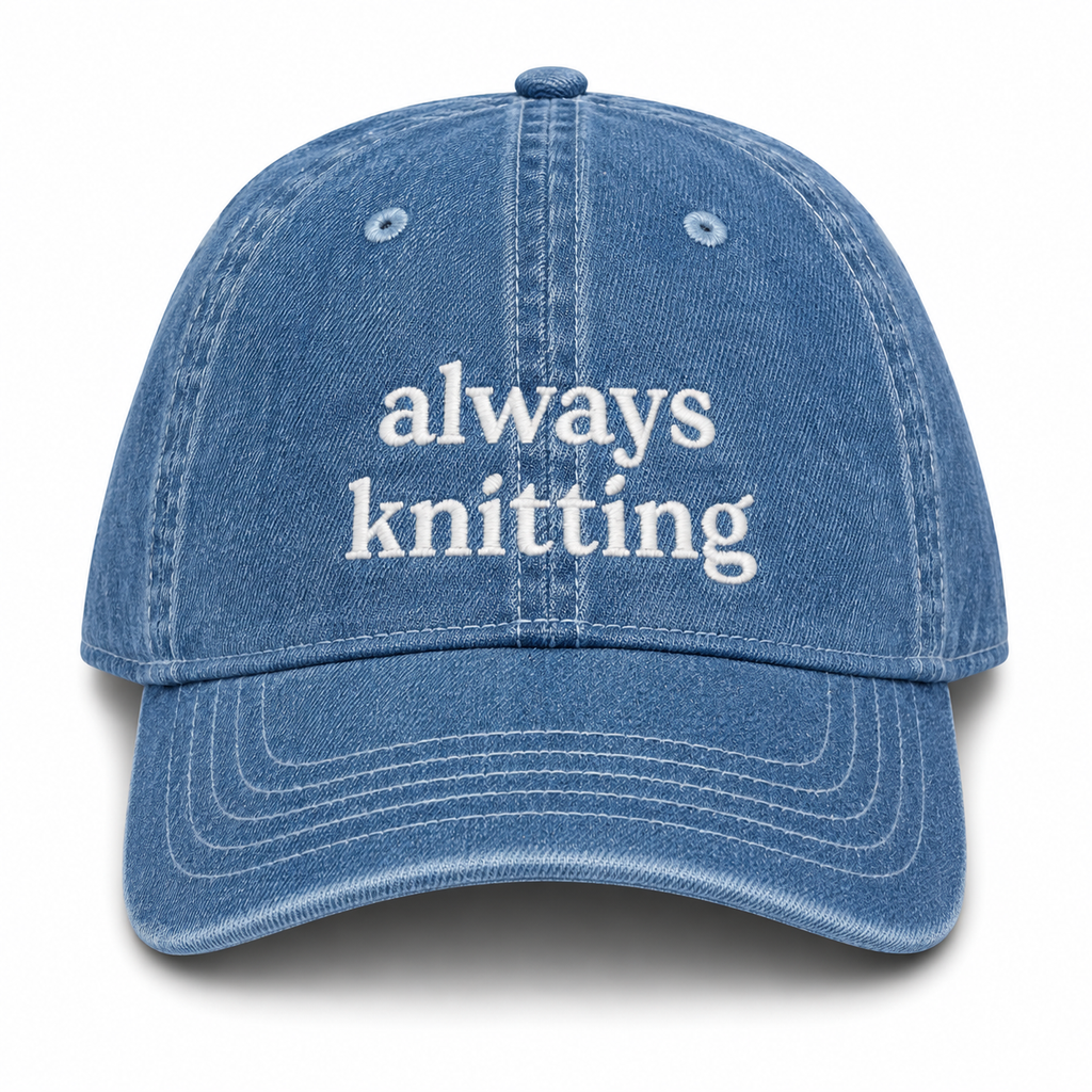 Blue denim cap with 'always knitting' text on a white background