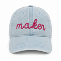 Light blue denim cap with 'maker' embroidered in pink on a white background