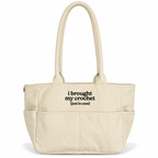 A cream-colored canvas tote bag with black printed text reading 'i brought my crochet (just in case)' on the front pocket, set against a plain white background.