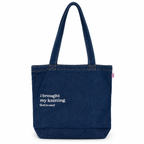 A dark blue denim tote bag with white printed text reading 'i brought my knitting (just in case)' on the front, set against a plain white background.