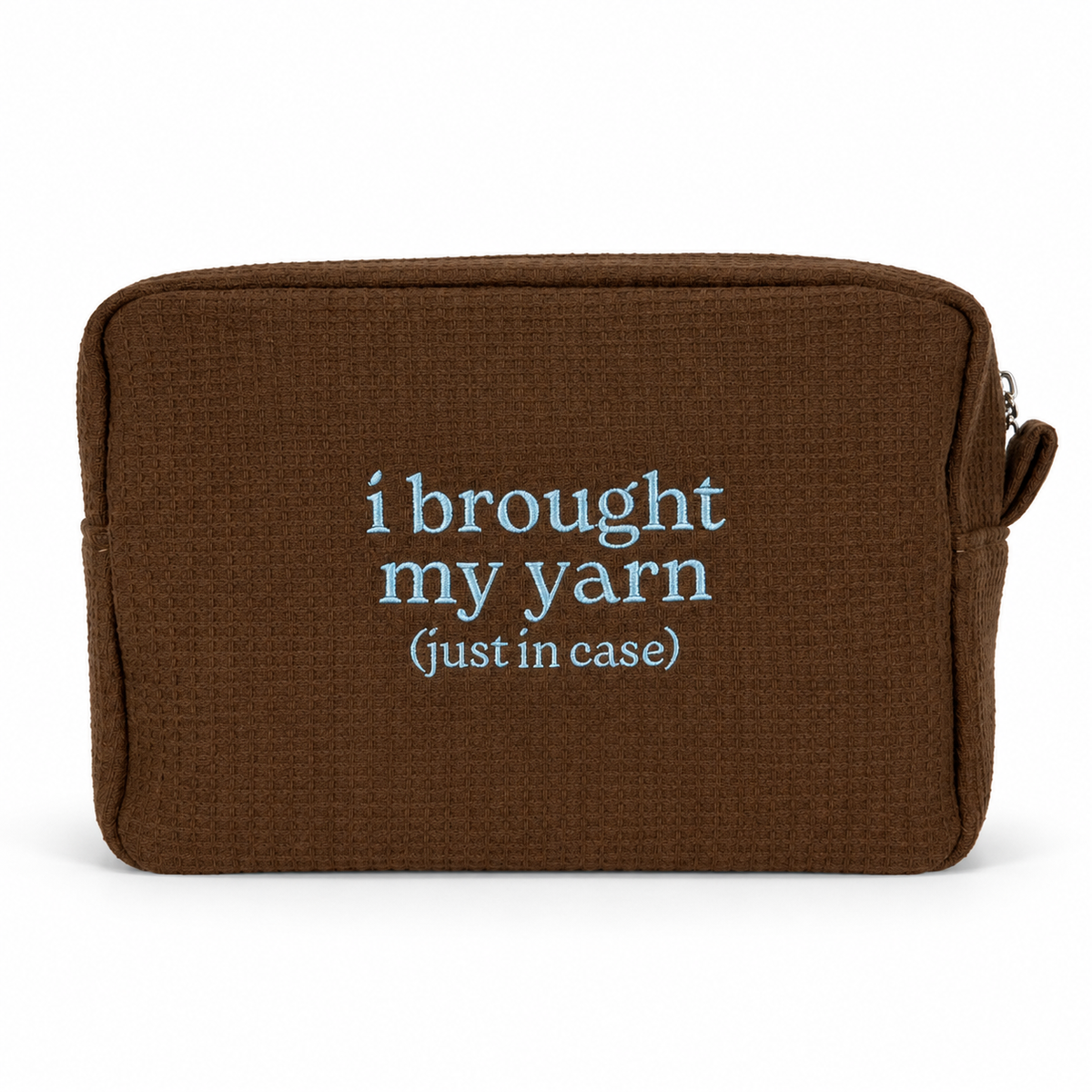 A brown textured zippered pouch with the phrase 'i brought my yarn (just in case)' printed in light blue text on the front, shown against a plain white background.