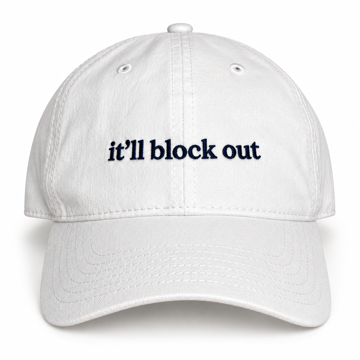 White dad hat with navy “It’ll Block Out” mini text embroidery.