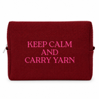 A dark red textured waffle-weave zippered pouch with bright pink embroidered text reading 'KEEP CALM AND CARRY YARN' on a white background.