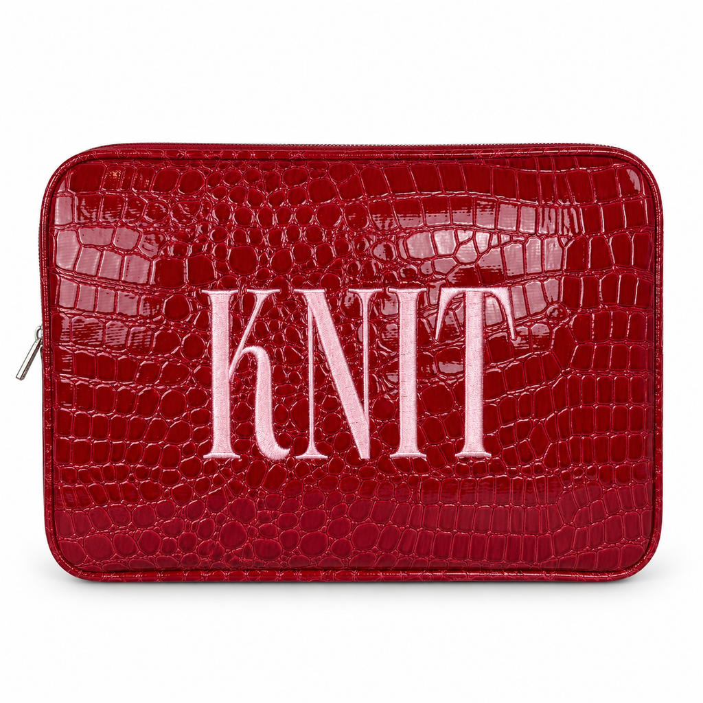 A red crocodile-embossed zippered pouch with the word 'KNIT' in large light pink letters across the front, shown on a plain white background.