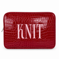 A red crocodile-embossed zippered pouch with the word 'KNIT' in large light pink letters across the front, shown on a plain white background.