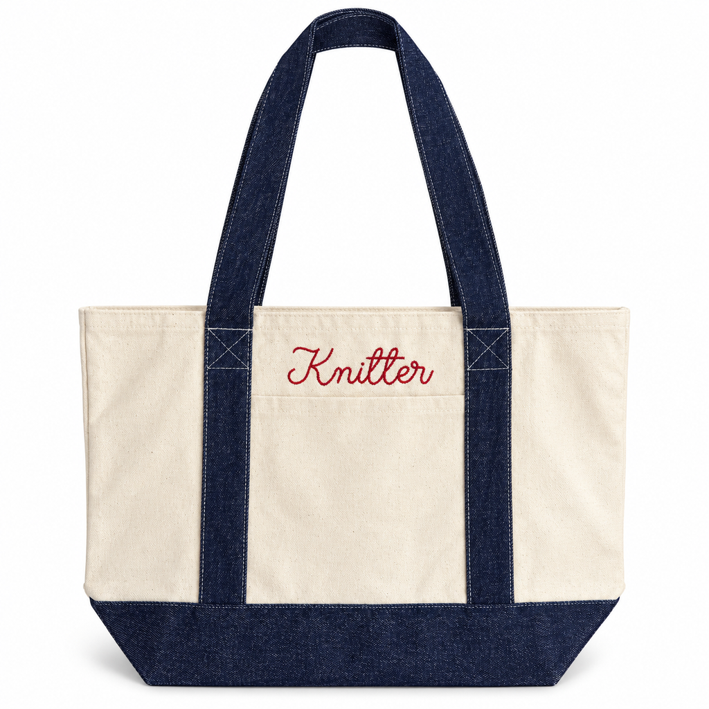 A canvas tote bag with an off-white body, dark navy blue handles and bottom trim, and red embroidered text reading 'Knitter' on the front pocket, shown on a plain white background.