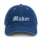 Blue cap with 'Maker' embroidered on a white background