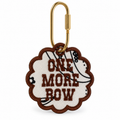 An embroidered keychain tag with a scalloped edge, featuring the text 'ONE MORE ROW' in brown on a cream background with a black-and-white striped pattern, attached to a gold carabiner.