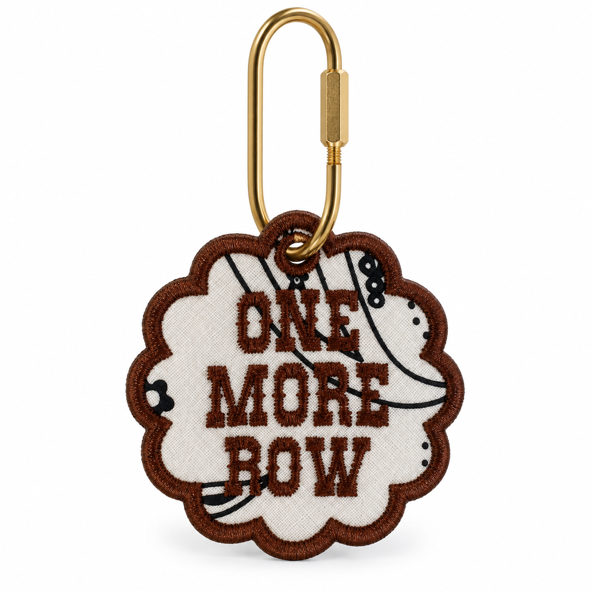 An embroidered keychain tag with a scalloped edge, featuring the text 'ONE MORE ROW' in brown on a cream background with a black-and-white striped pattern, attached to a gold carabiner.