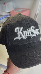 Black denim hat with Knit Sox white puff embroidery and metallic silver embroidered detail