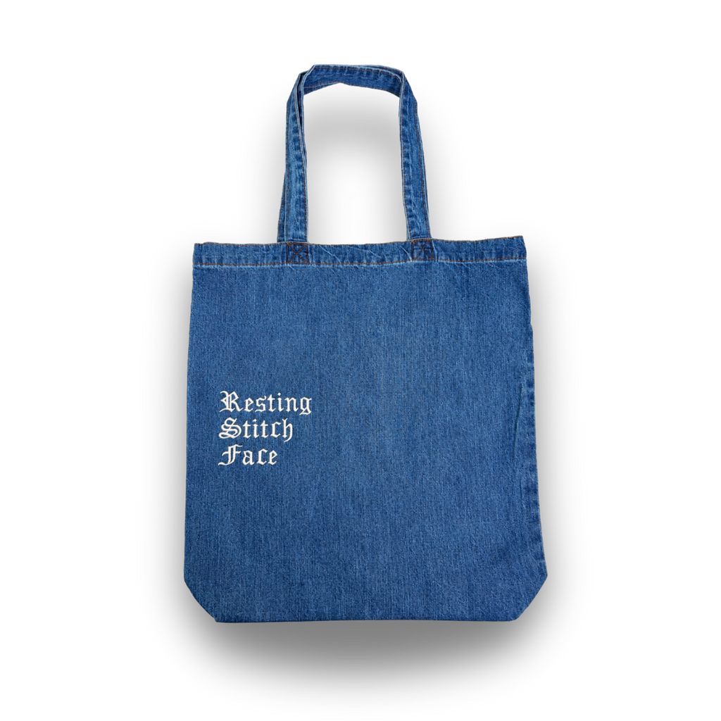 Blue denim tote bag with 'Resting Stitch Face' text on a white background