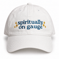 White dad hat with slate blue “Spiritually On Gauge” embroidery and metallic gold stars.