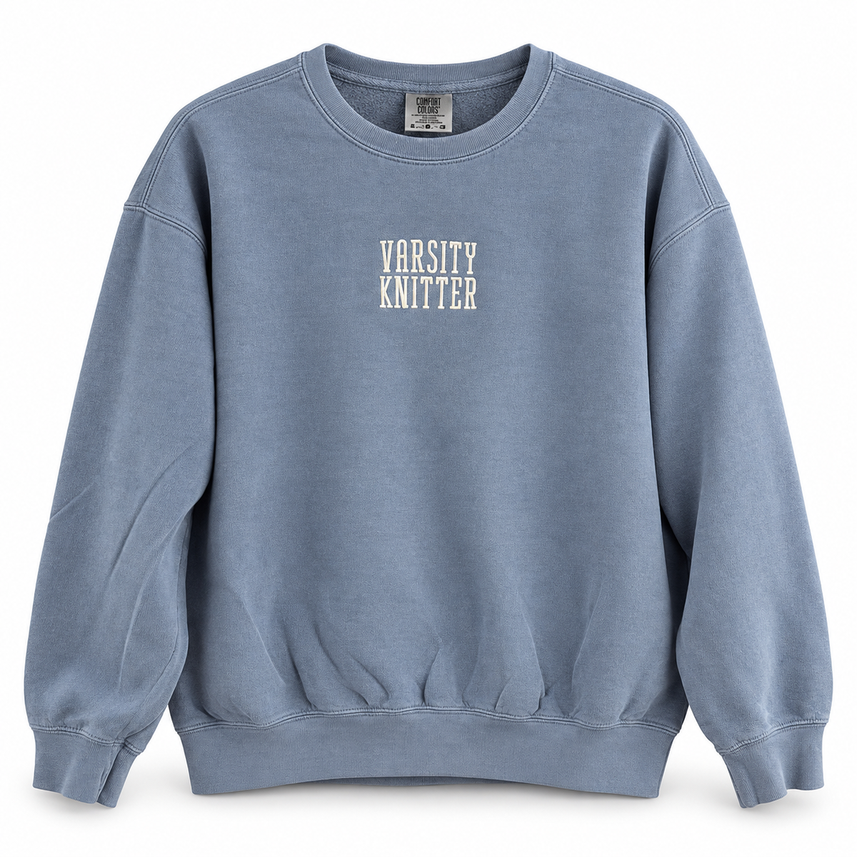 A dusty blue crewneck sweatshirt with 'VARSITY KNITTER' printed in white block letters on the chest, displayed against a clean white background.