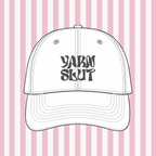 White hat mockup with charcoal upside-down Yarn Slut embroidery on a pink striped background